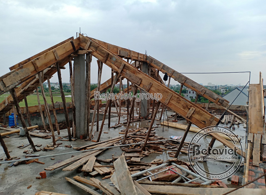 Không gian tầng trên của công trình đang trong giai đoạn đổ bê tông mái, nhìn từ góc rộng. Hệ thống cốp pha gỗ được dựng c…