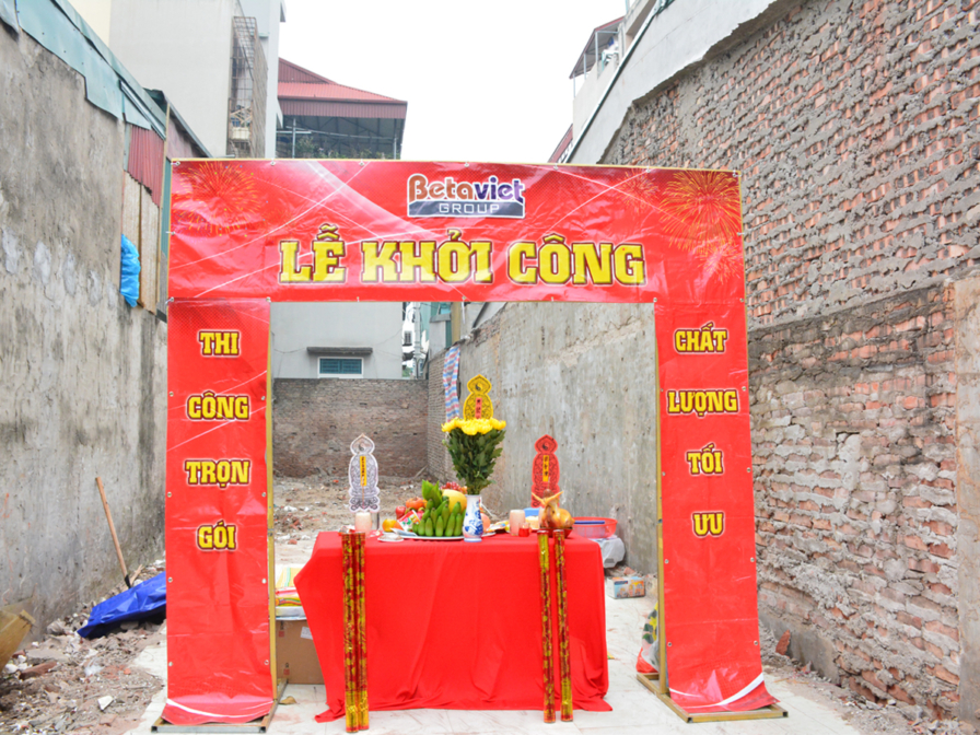 Cận cảnh mâm lễ vật truyền thống được bày biện trên bàn đỏ trong lễ khởi công. Phía sau là cổng chào "Lễ Khởi Công" và khu…