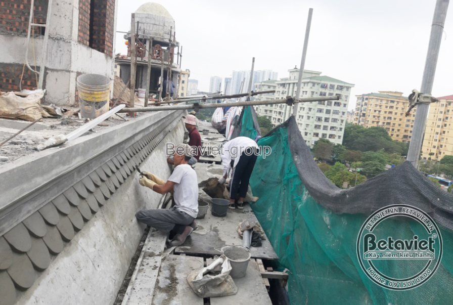 Toàn cảnh mái vòm và các chi tiết trang trí trên đỉnh biệt thự đang được thi công, với giàn giáo và lưới bảo hộ. Các đường…