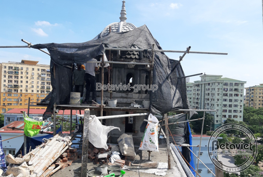 Cận cảnh chi tiết phào chỉ và hoa văn trang trí trên mặt tiền biệt thự đang được hoàn thiện, với giàn giáo bao quanh. Các…
