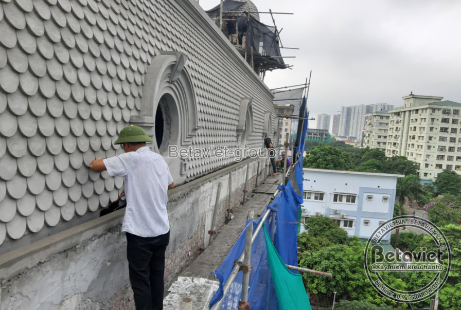 Chi tiết thi công phần mái vòm của biệt thự phố, nhìn từ trên cao xuống. Công nhân đang tỉ mỉ ốp các viên ngói vảy cá màu…