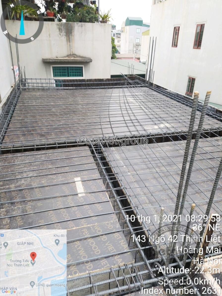 Lưới thép sàn được buộc thành ô vuông đều, đường dầm chia phòng hiện rõ trên nền thép. Không gian mở nhìn ra khu dân cư xu…