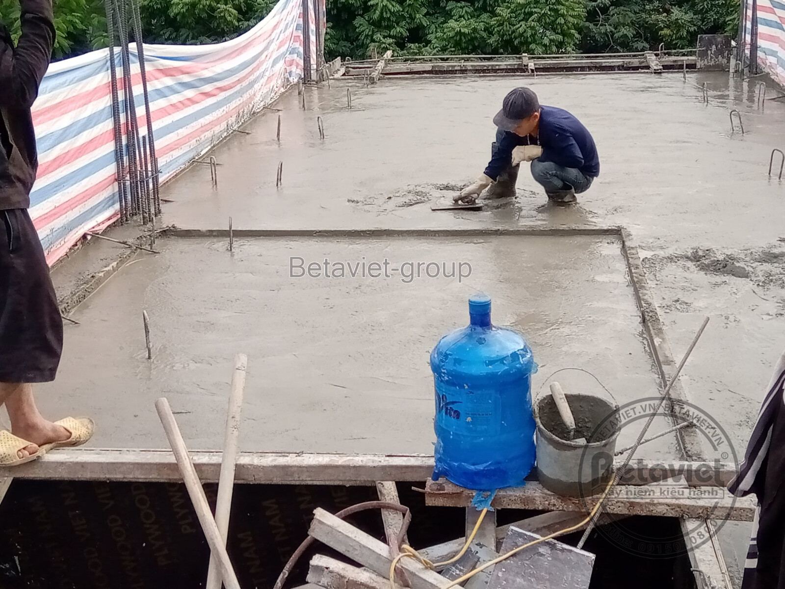 Công nhân đang đổ bê tông sàn cho một tầng của biệt thự, với hệ thống cốt thép và ván khuôn đã được lắp đặt sẵn. Ánh sáng…
