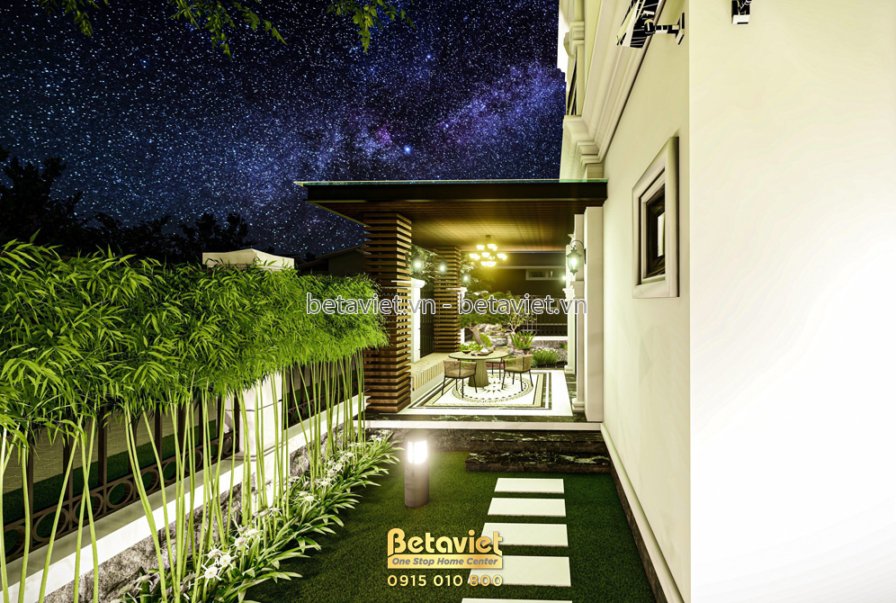 Hành lang bên hông rợp bóng tre dày đặc, lối cỏ dẫn tới khu pavilion có mái gỗ và đèn thả phía xa, không gian xanh mát khé…