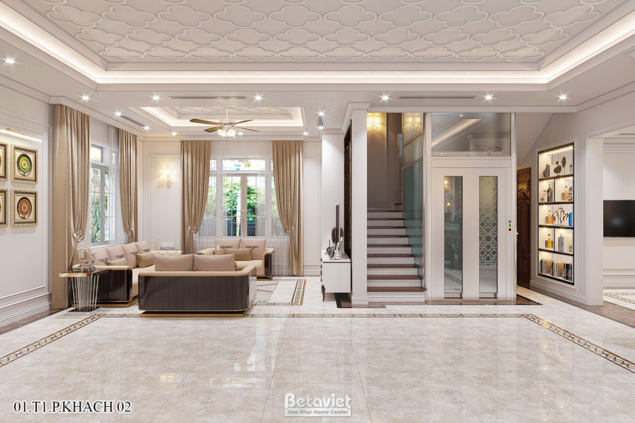 Đại sảnh với sofa nâu sẫm, thang máy kính bên cạnh cầu thang, kệ tủ trắng trang trí, trần thạch cao hoa văn và cửa sổ rèm…