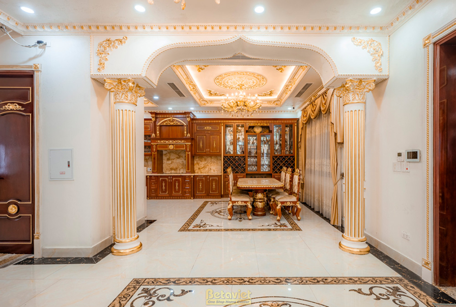 Không gian sảnh và cầu thang tân cổ điển, với sàn lát gạch họa tiết đối xứng, tường ốp phào chỉ vàng đồng. Cầu thang tay v…
