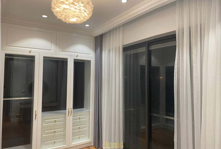 Tủ quần áo âm tường màu trắng với cánh cửa pano, thiết kế tân cổ điển nhẹ nhàng. Tường ốp phào chỉ trắng, sàn gỗ, tạo khôn…