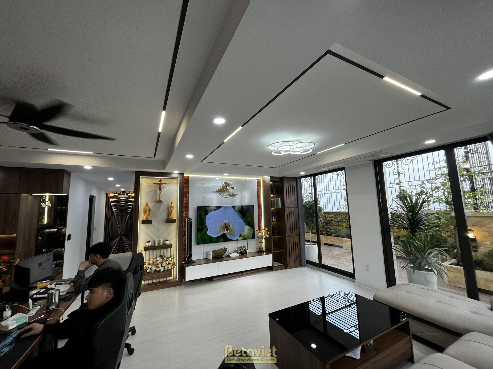 Toàn cảnh phòng khách và khu vực làm việc tích hợp, nhìn từ phía cửa. Nội thất hiện đại với tông trắng, nâu gỗ chủ đạo. Tr…