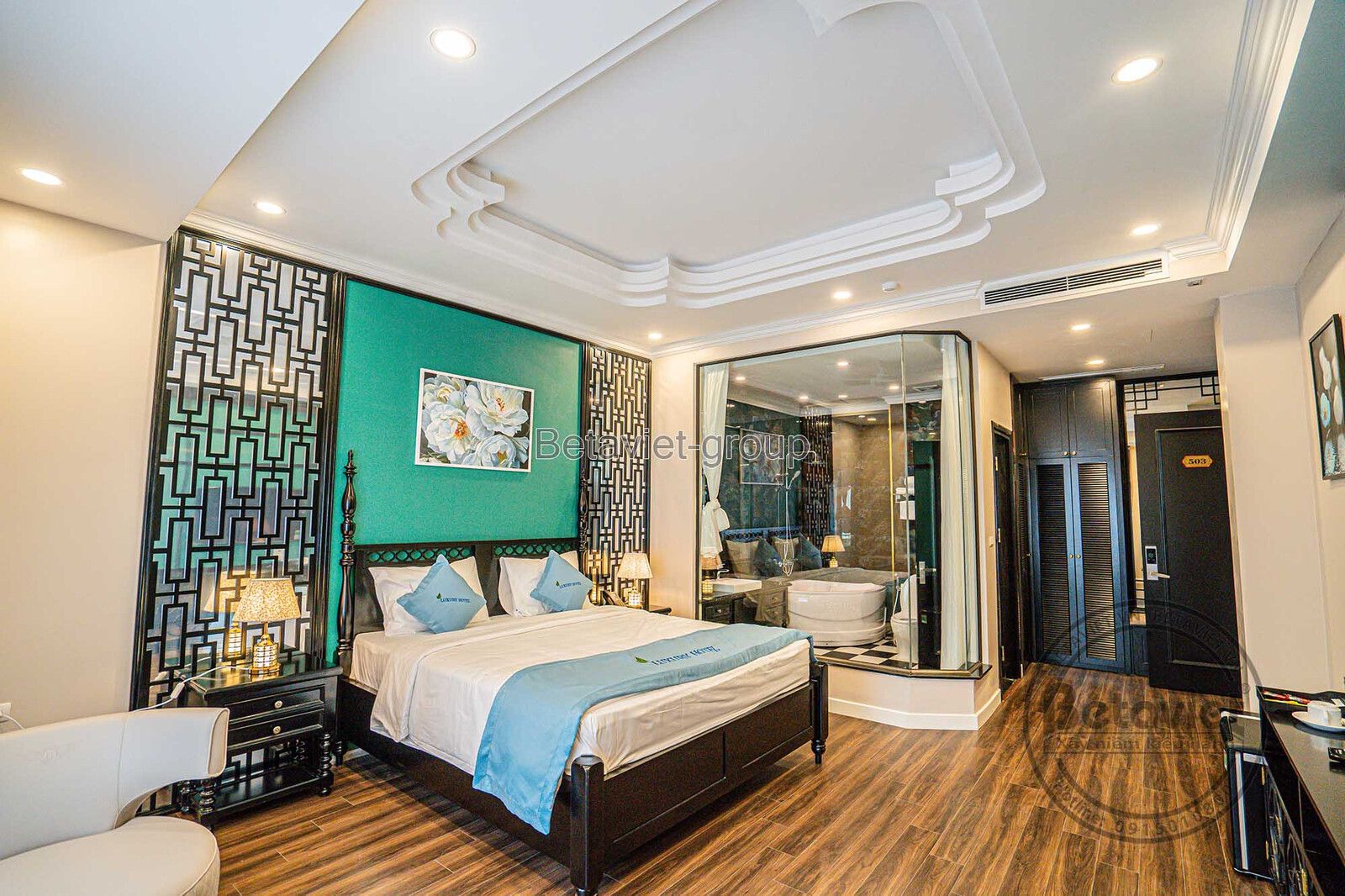 Phòng ngủ khách sạn với thiết kế mở, kết nối trực tiếp với khu vực phòng tắm. Giường ngủ bọc nệm, gương lớn hình oval và s…