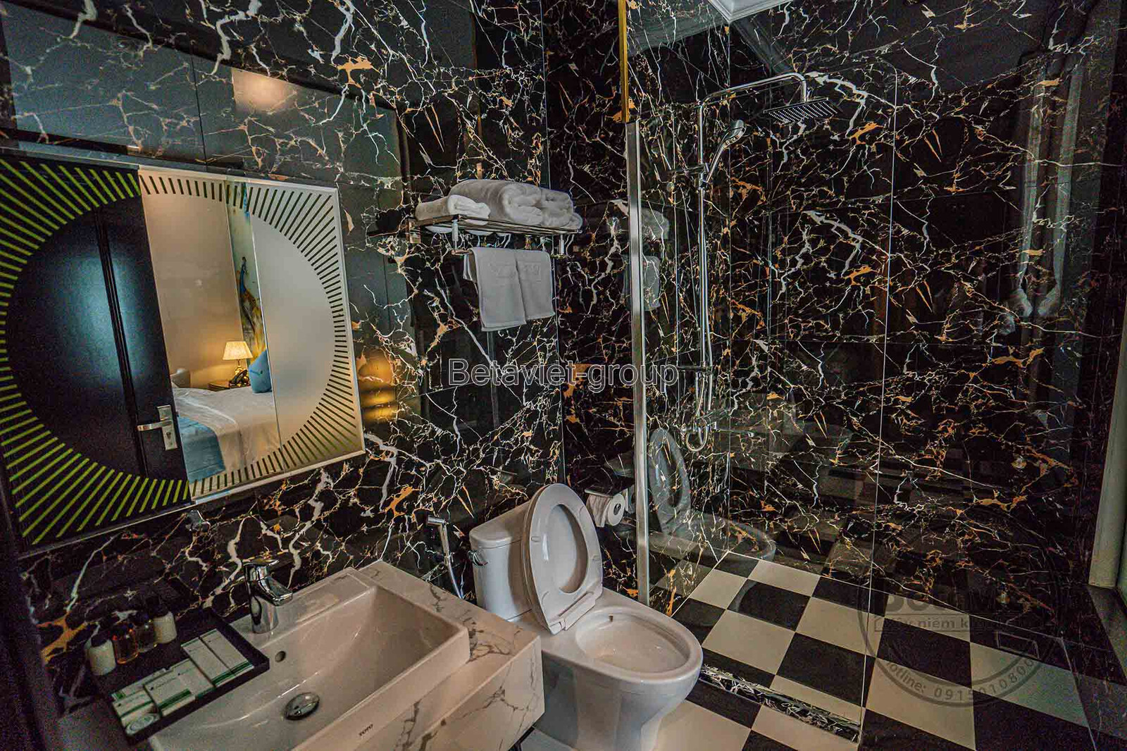 Khu vực phòng tắm đứng với tường ốp đá marble đen vân vàng sang trọng. Sàn gạch caro đen trắng và vòi sen hiện đại tạo sự…