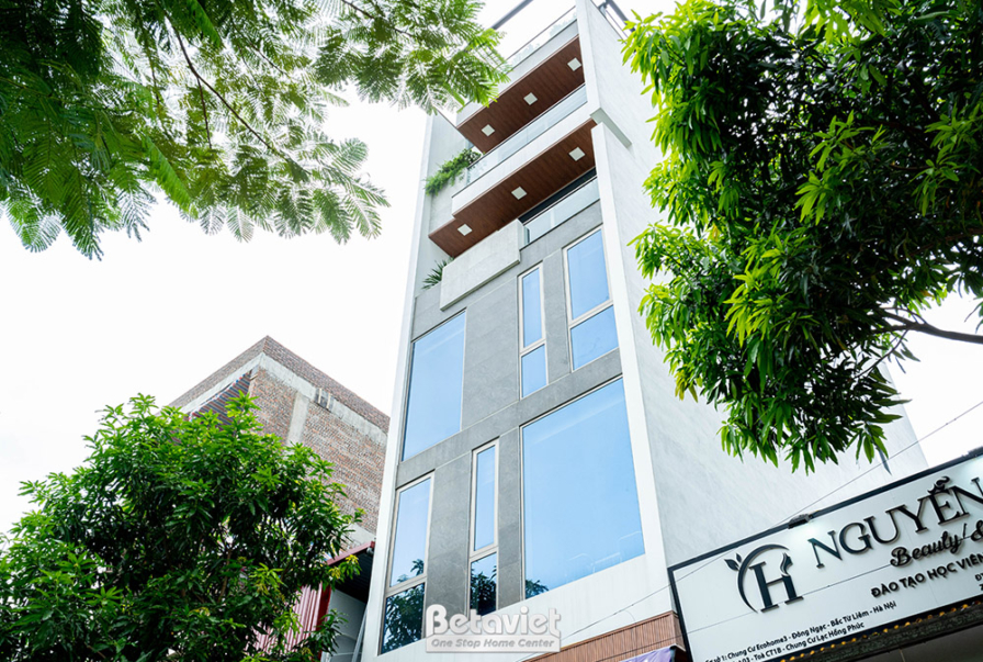 Mặt tiền công trình nhà phố 6 tầng đã hoàn thiện, nhìn từ góc thấp, nổi bật với thiết kế hiện đại và cây xanh. Các mảng ốp…