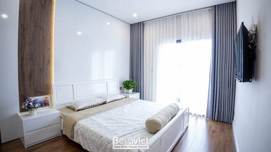 Góc nhìn khác của phòng ngủ master đã hoàn thiện, tập trung vào giường đôi và tủ đầu giường. Tường ốp gỗ và gương trang tr…