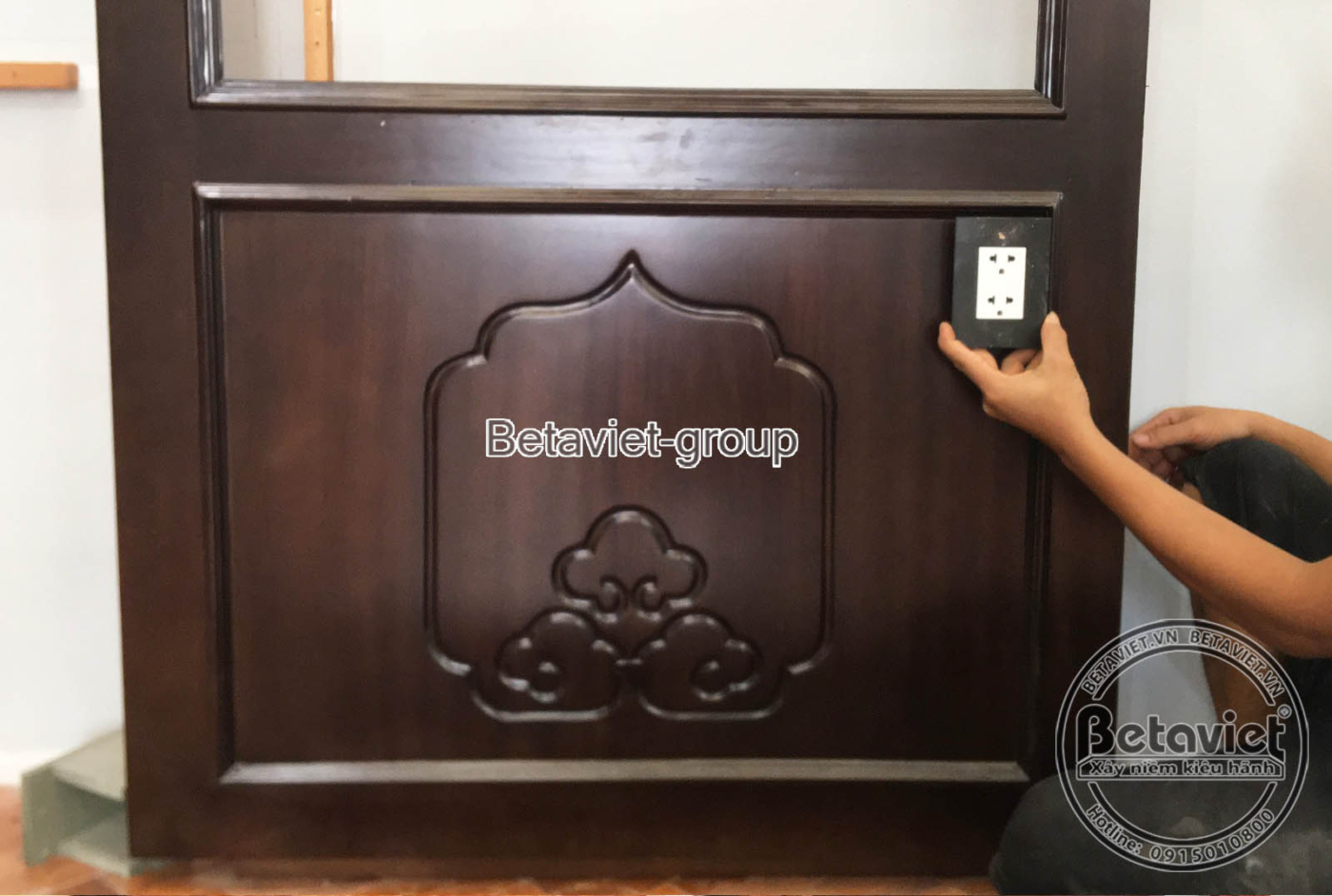 Công nhân đang lắp đặt kệ gỗ âm tường trong không gian nội thất, cho thấy quá trình hoàn thiện các chi tiết trang trí, đảm…