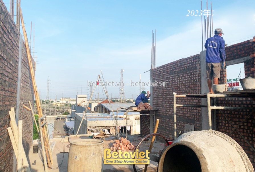 Công nhân đang xây tường gạch bên trong công trình, chuẩn bị cho việc trát. Vật liệu xây dựng được tập kết gọn gàng, đảm b…
