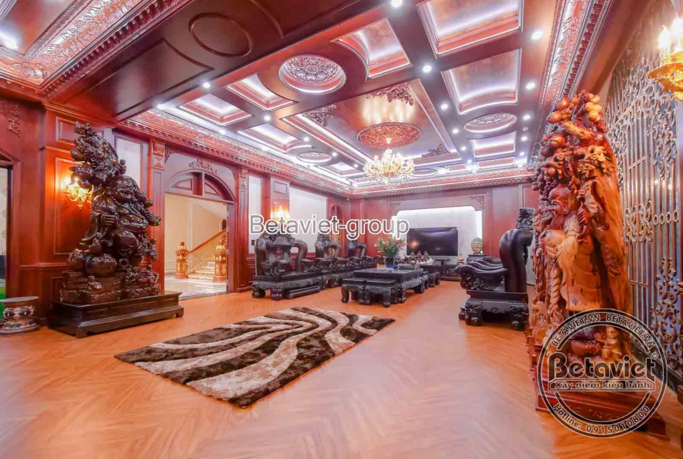 Toàn cảnh phòng khách gỗ từ trên cao, cho thấy sự bề thế của bộ bàn ghế gỗ chạm khắc và cách bố trí không gian hài hòa. Tr…