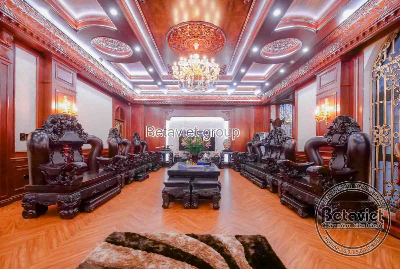Phòng sinh hoạt chung hoặc phòng khách thứ hai, với bộ bàn ghế gỗ tự nhiên chạm khắc cầu kỳ, mang phong cách Indochine hoặ…