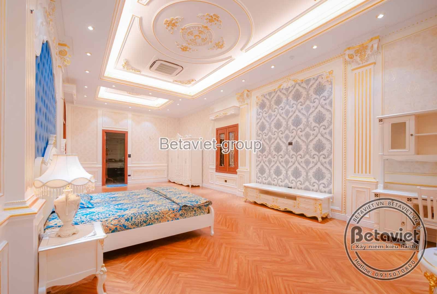 Góc nhìn khác của phòng ngủ, cho thấy tủ quần áo âm tường màu trắng kem với phào chỉ cổ điển, tối ưu không gian. Bàn trang…