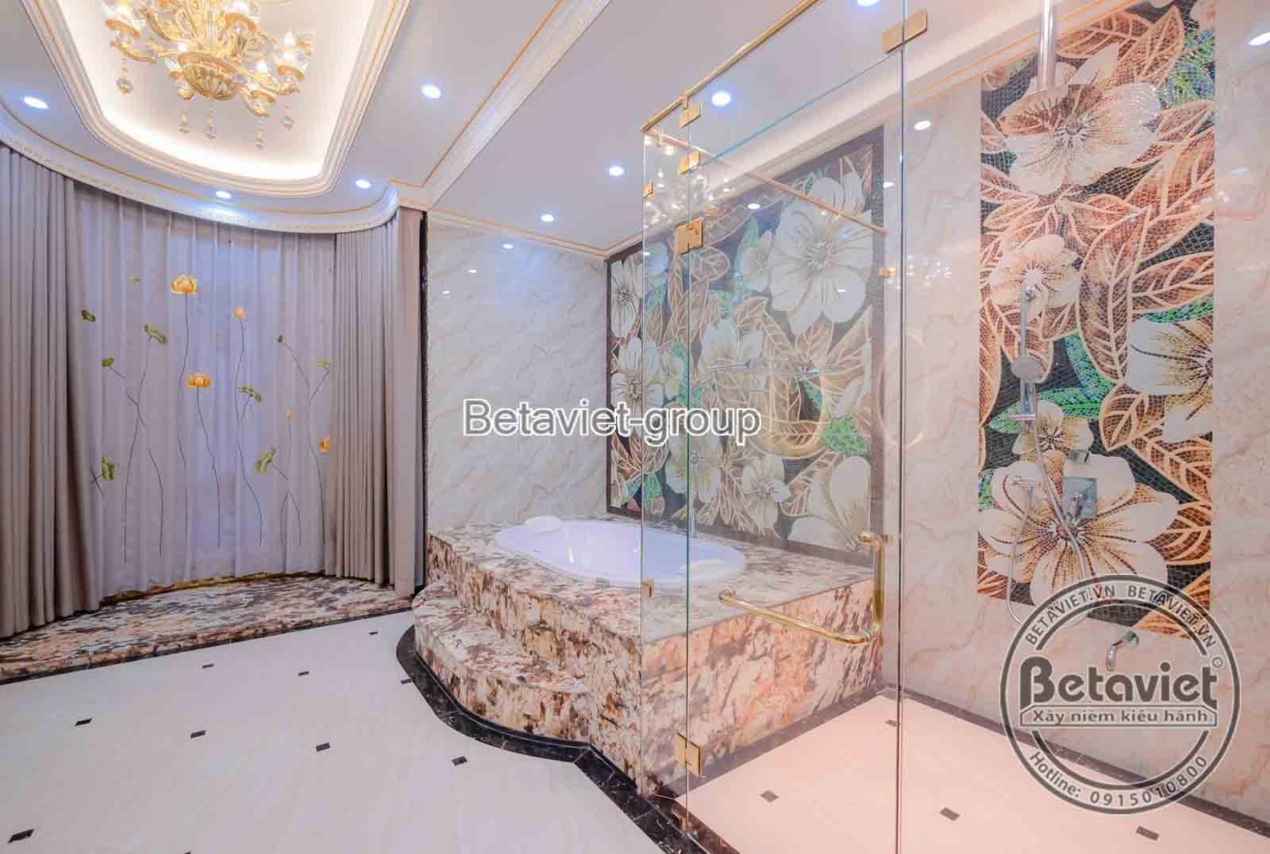 Phòng tắm với bồn tắm độc lập ốp đá họa tiết hoa văn, vách kính tắm đứng hiện đại. Sàn lát đá vân mây, tường ốp gạch họa t…