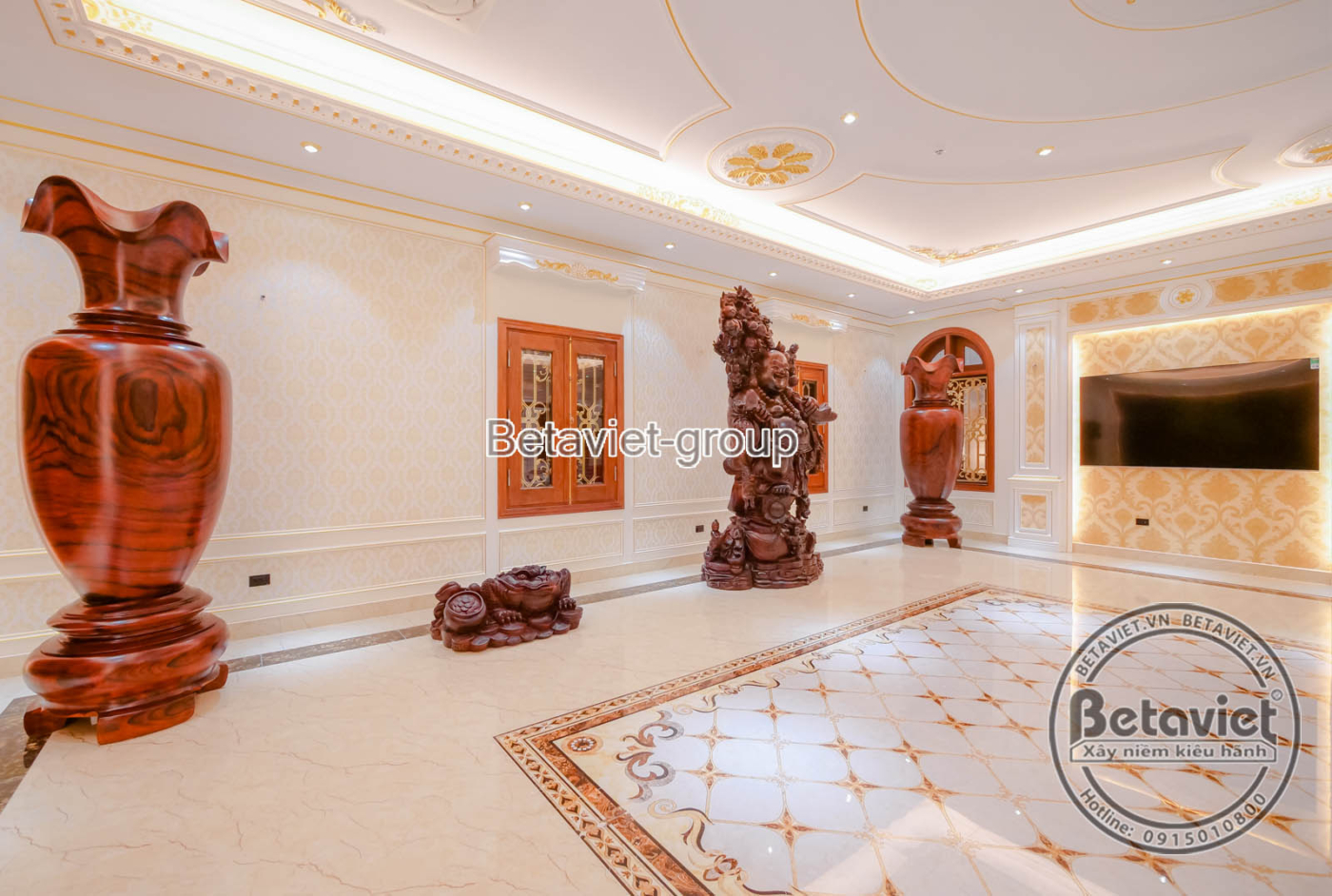Hành lang hoặc sảnh chờ với sàn đá vân mây, tường ốp hoa văn dát vàng tinh xảo. Điểm nhấn là bình gốm lớn đặt ở góc, trần…