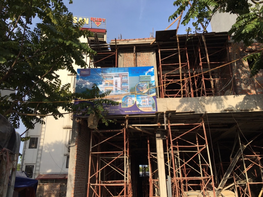 Tổng thể công trình nhà phố đang trong giai đoạn thi công phần thô, nhìn từ góc thấp lên cao. Khung xương bê tông cốt thép…