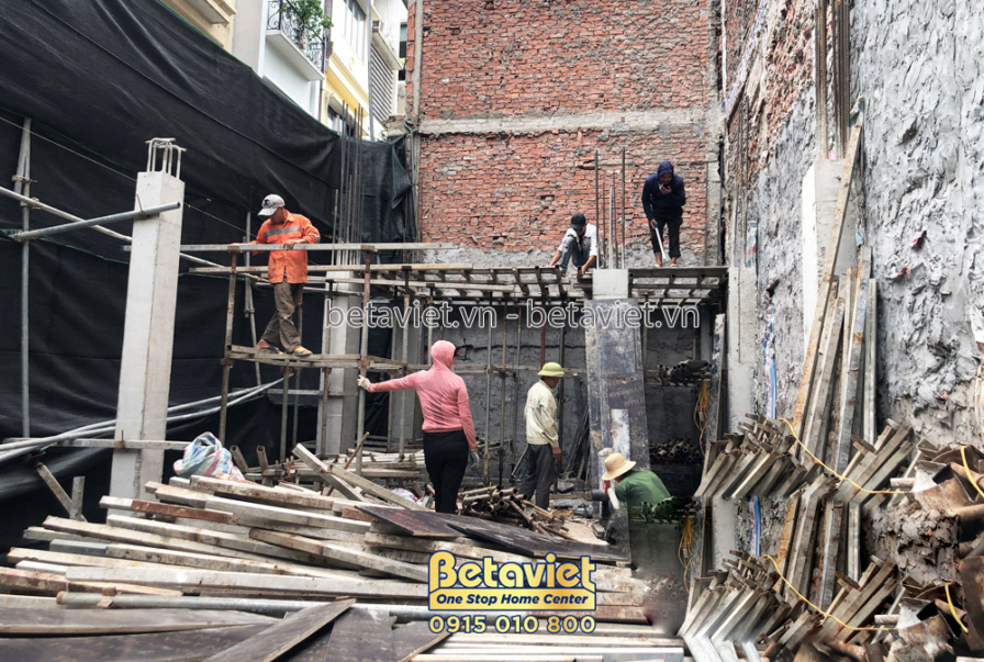 Công nhân đang làm việc trên giàn giáo để xây dựng phần thô của công trình. Giàn giáo bằng thép và gỗ được dựng cao, cho t…