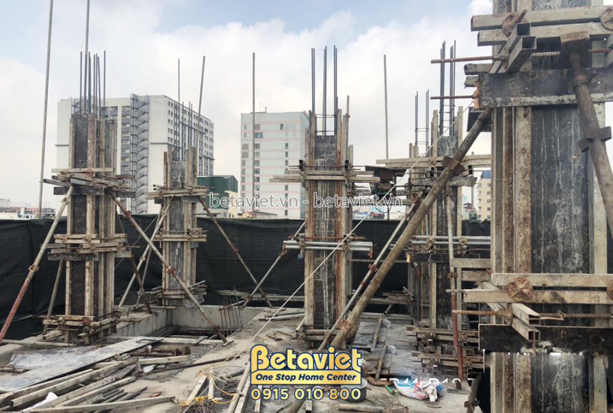 Giàn giáo và cốt thép đang được dựng để đổ bê tông sàn hoặc dầm. Bố cục nhìn từ dưới lên, cho thấy cấu trúc khung xương vữ…