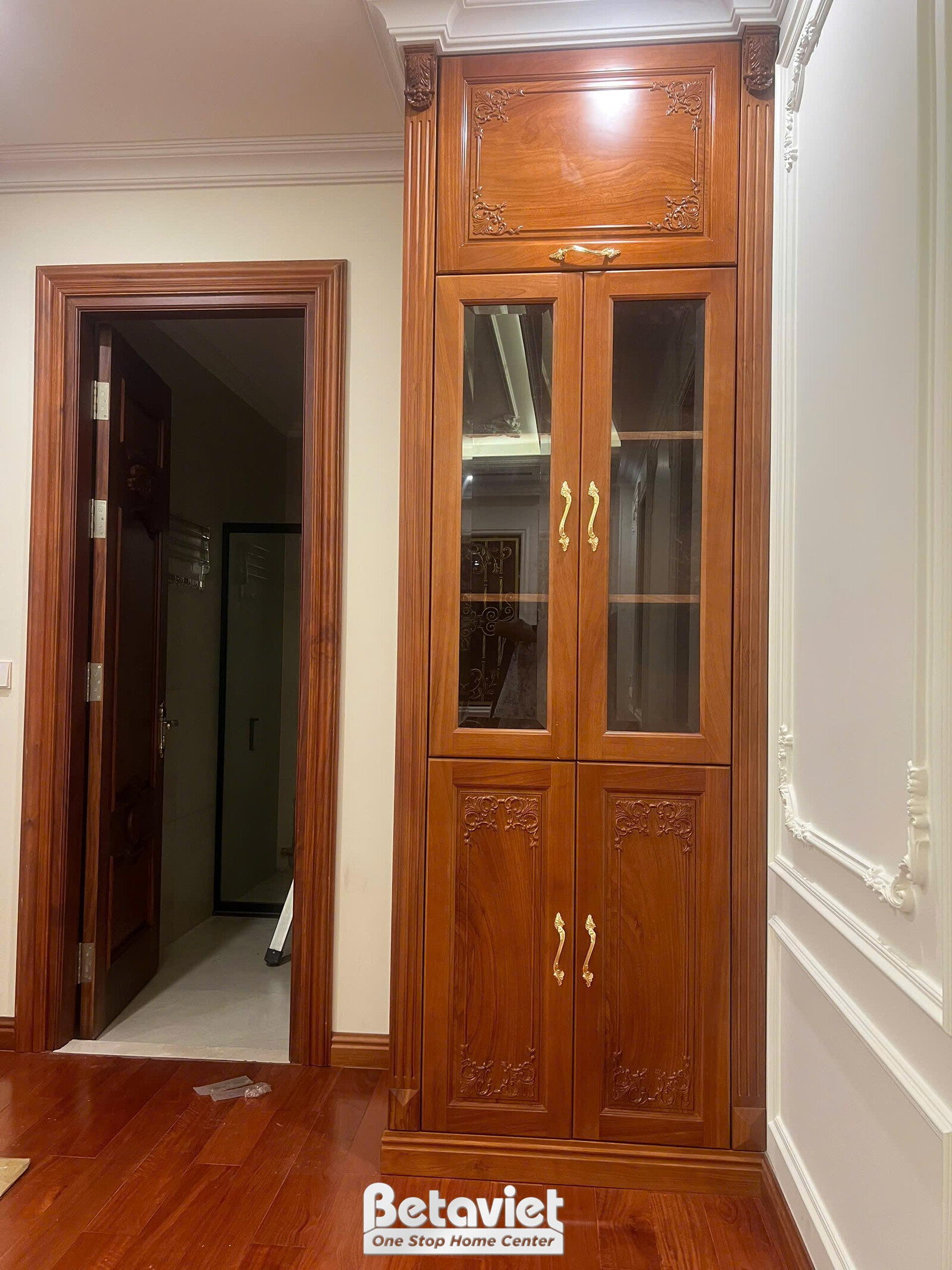 Hành lang hoặc lối đi với cửa gỗ tự nhiên màu nâu đỏ, kết hợp tủ trưng bày âm tường có kính. Trần nhà thạch cao với phào c…
