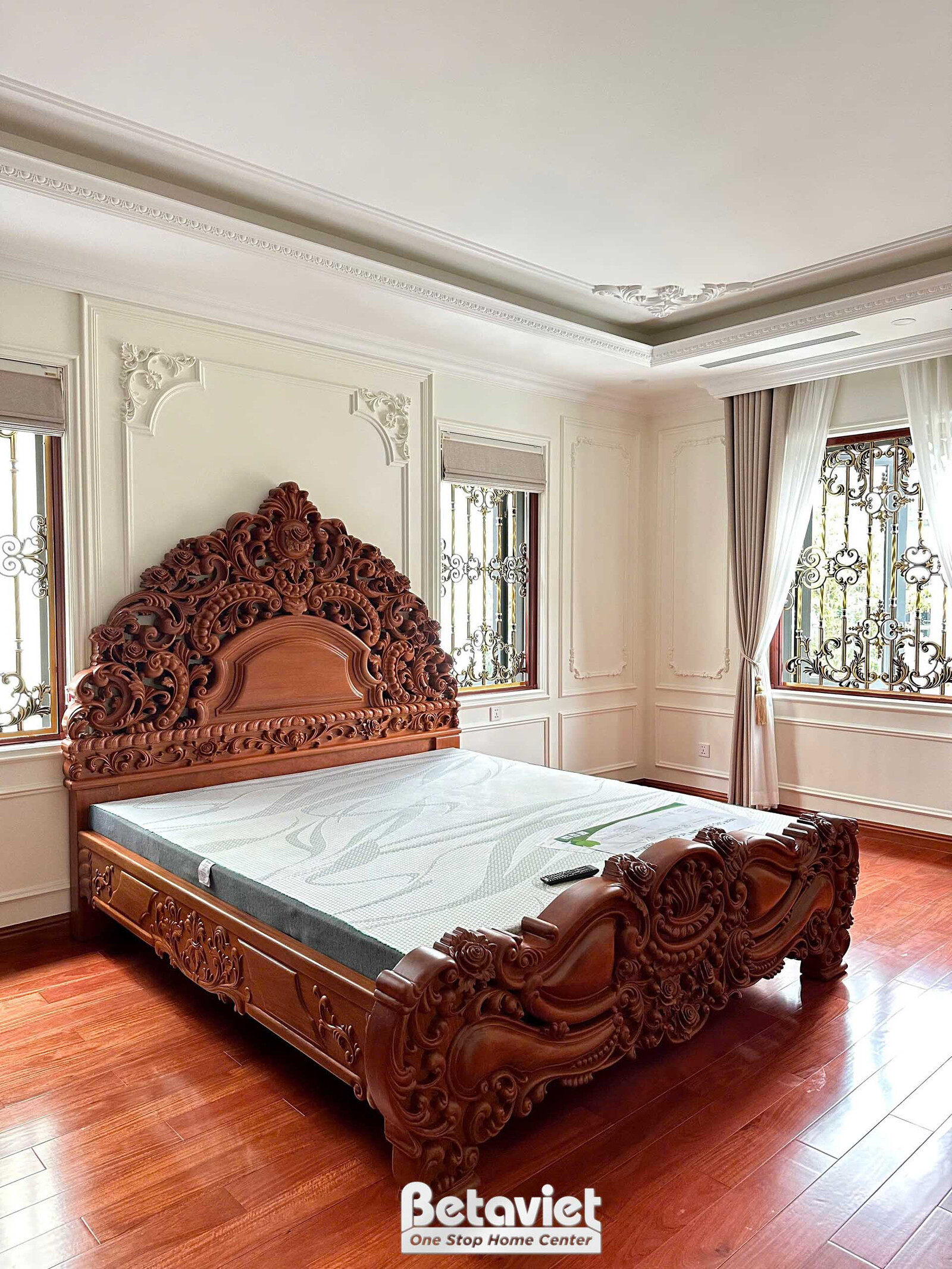 Giường ngủ gỗ chạm khắc tinh xảo, màu nâu đỏ, là điểm nhấn chính trong phòng ngủ. Tường ốp phào chỉ trắng, rèm cửa màu be…