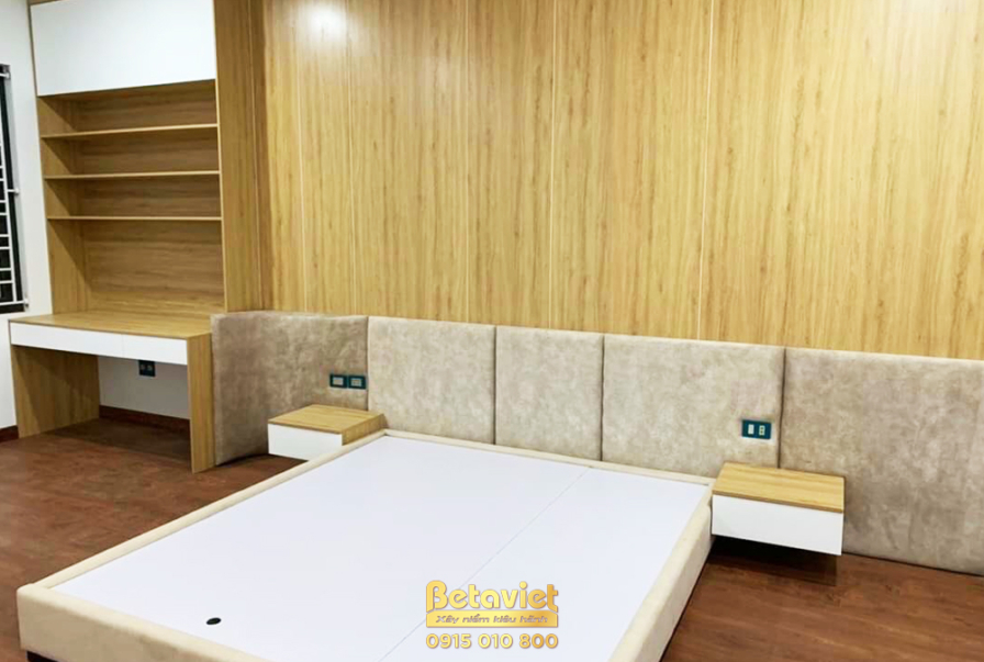 Phòng ngủ đã hoàn thiện với giường bục thấp màu trắng, vách đầu giường bọc nệm màu be. Tab đầu giường và bàn trang điểm li…