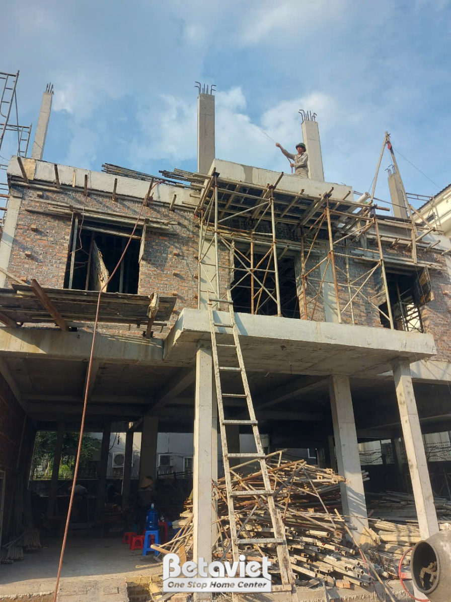 Không gian bên trong ngôi nhà phố đang thi công phần thô, nhìn từ tầng dưới lên. Các cột bê tông và dầm sàn đã được đổ, gi…