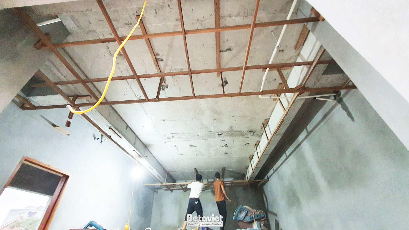 Không gian bên trong ngôi nhà phố đang thi công phần thô, nhìn từ góc rộng. Các bức tường đã được trát sơ bộ, hệ thống điệ…
