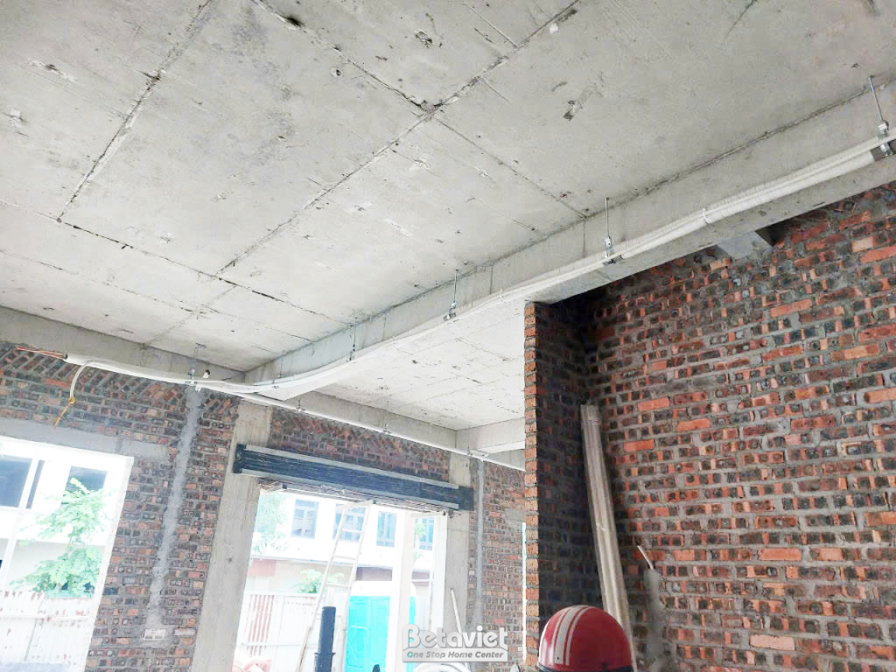 Không gian bên trong ngôi nhà phố đang thi công phần thô, nhìn từ góc rộng. Các bức tường gạch đã xây xong, trần bê tông đ…