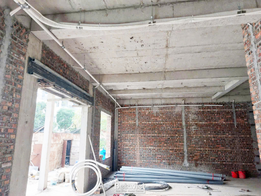 Không gian bên trong ngôi nhà phố đang thi công phần thô, nhìn từ góc rộng. Các bức tường gạch đã xây xong, hệ thống ống n…