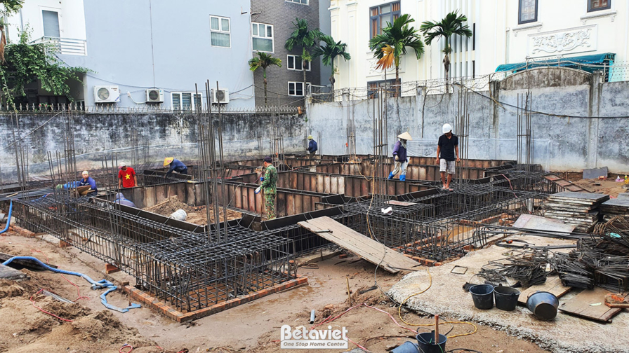 Công nhân đang thực hiện công việc thi công móng nhà phố, với hệ thống sắt thép và ván khuôn. Các hố móng đã được đào, chu…