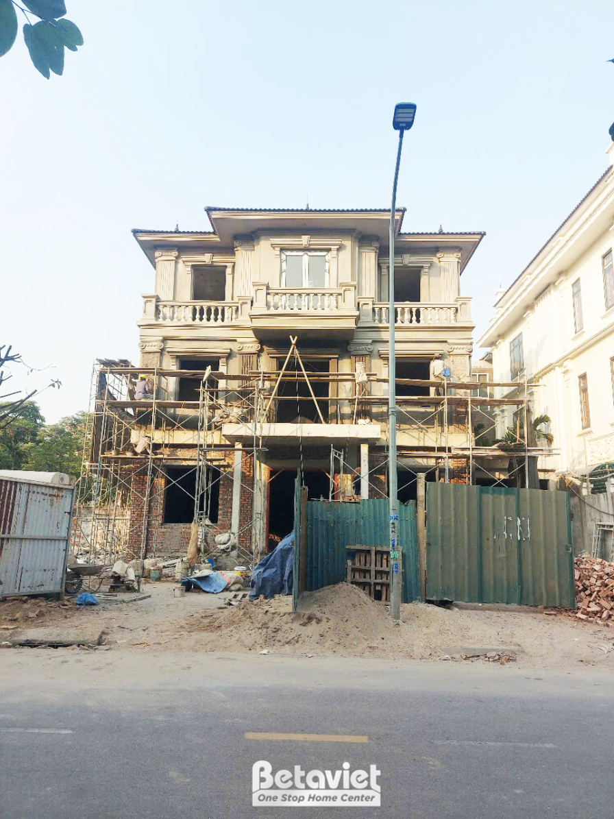 Toàn cảnh ngôi nhà phố 3 tầng đang thi công phần thô, nhìn từ góc thấp. Các tầng đã được xây dựng, giàn giáo bao quanh, ch…