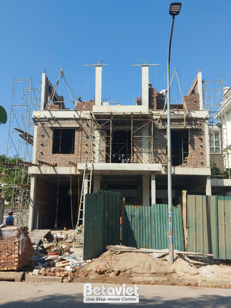 Ngôi nhà phố 3 tầng đang thi công phần thô, nhìn từ phía trước. Các bức tường gạch đã xây xong, khung cửa sổ đã được lắp đ…