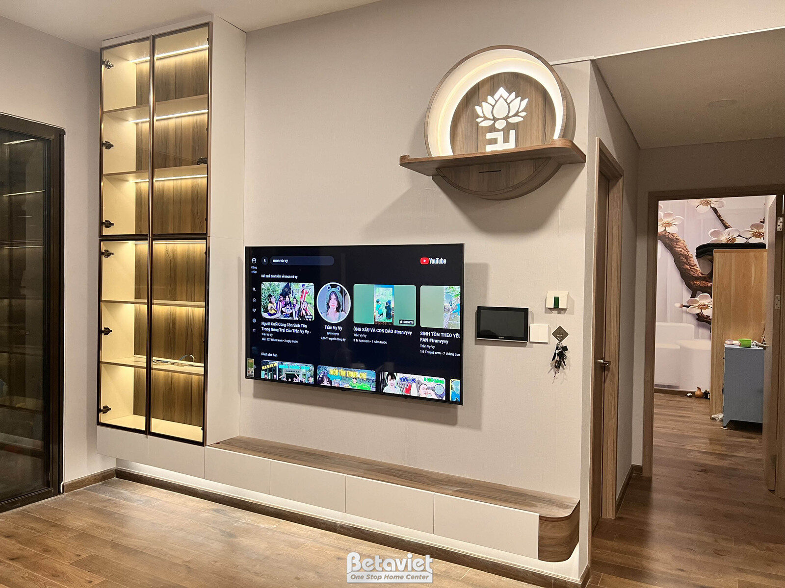 Cận cảnh khu vực kệ tivi treo tường và tủ trang trí đã hoàn thiện. Kệ tivi màu trắng kết hợp hộc tủ gỗ nâu, phía trên là t…