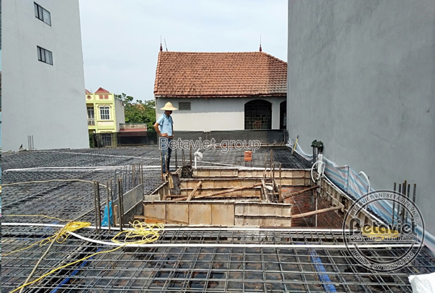 Sàn bê tông cốt thép đang được đan lưới dày đặc chuẩn bị đổ bê tông, công nhân đứng kiểm tra giữa nền thép. Phía sau là ng…