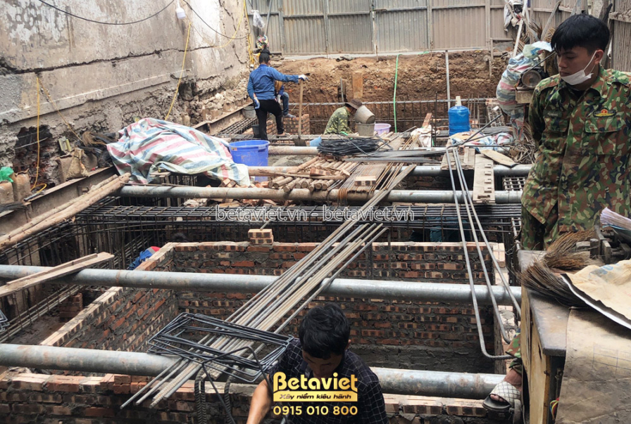 Mặt sàn trệt đang thi công cốt thép, lưới thép đan dày trải khắp nền, ống nhựa kỹ thuật đi âm sàn xen giữa các thanh thép…