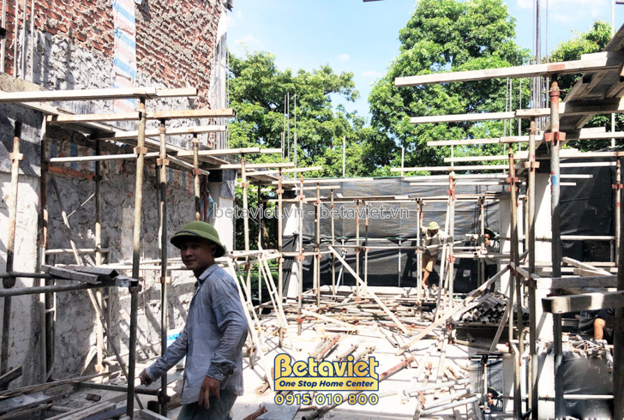 Công nhân đang làm việc trên giàn giáo để chuẩn bị đổ bê tông sàn tầng 3. Khung giàn giáo bằng thép và gỗ được dựng chắc c…
