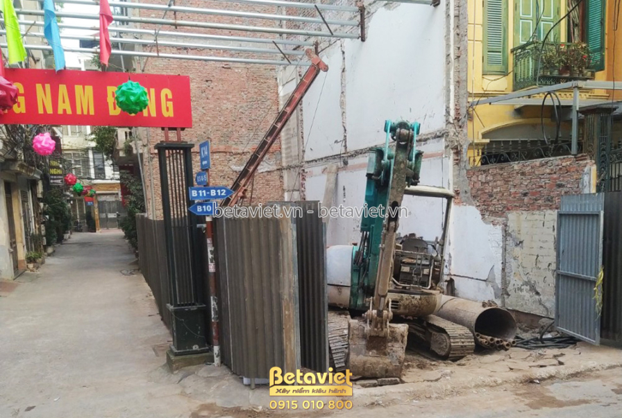 Cận cảnh máy ép cọc đang hoạt động trên công trường, với các cọc bê tông được chuẩn bị. Xung quanh là vật liệu xây dựng, c…