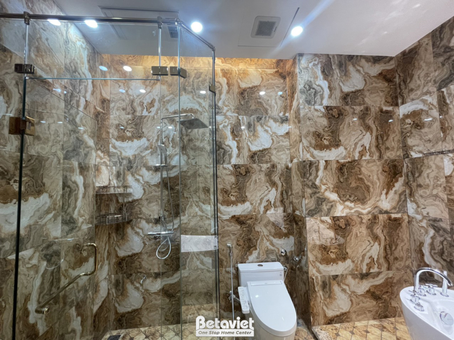 Phòng tắm hiện đại với vách kính cường lực phân chia khu vực tắm. Tường ốp đá vân nâu tự nhiên, tạo cảm giác sang trọng và…