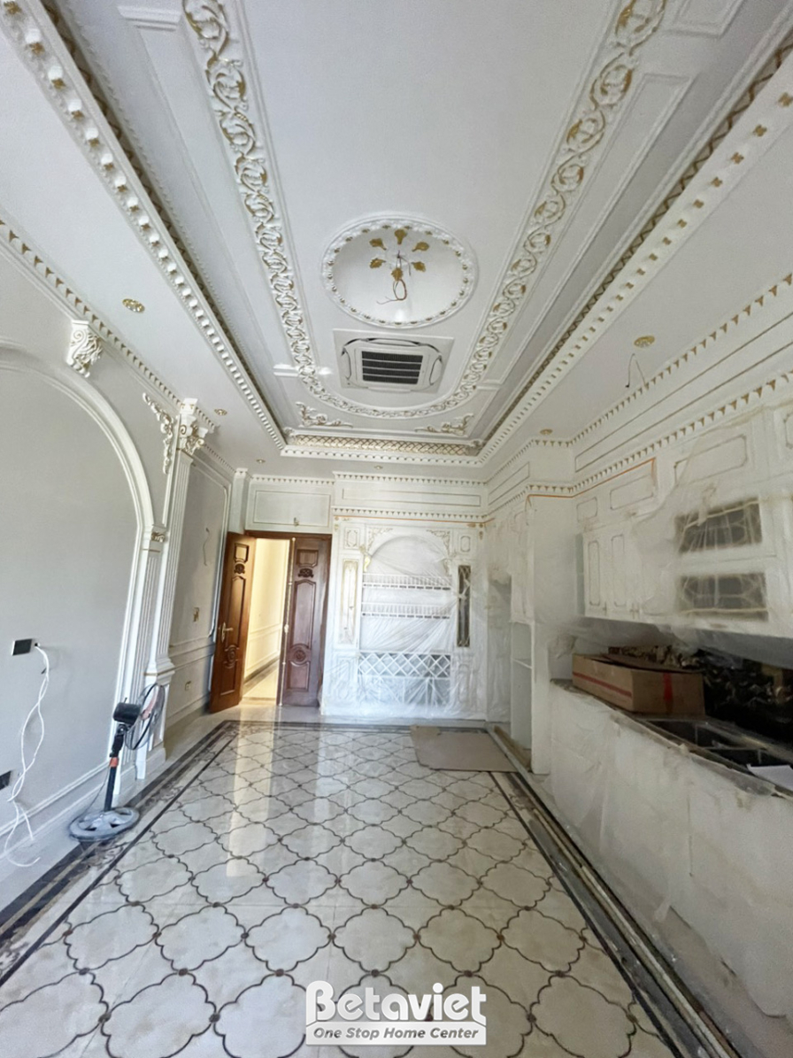 Không gian bếp phụ hoặc khu vực chuẩn bị với hệ tủ bếp trên và dưới màu trắng đơn giản. Sàn nhà ốp gạch họa tiết đen trắng…