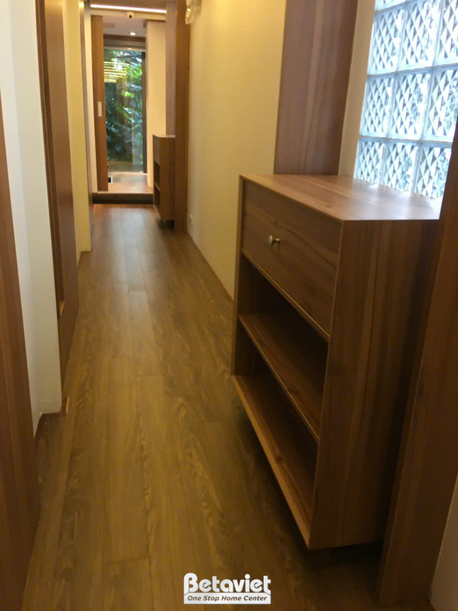 Không gian hành lang hoặc lối đi với tủ gỗ âm tường màu nâu. Sàn nhà lát gạch giả gỗ, tạo cảm giác ấm áp và liền mạch. Ánh…