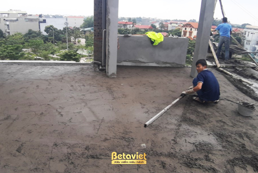 Không gian nội thất đang trong giai đoạn lát sàn gỗ, với các công nhân đang vận chuyển và lắp đặt từng tấm ván gỗ. Sàn nhà…