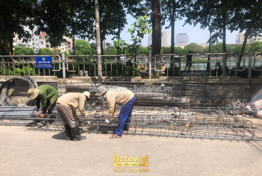 Công nhân đang buộc thép móng trên nền đất đã được san ủi. Khung thép móng được chuẩn bị kỹ lưỡng, xung quanh là vật liệu…