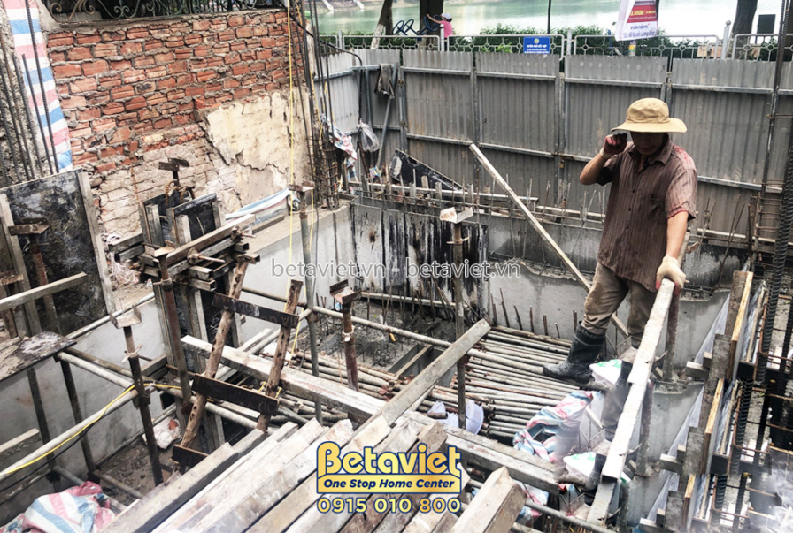 Công nhân đang làm việc trên giàn giáo để chuẩn bị đổ bê tông sàn tầng 1. Khung giàn giáo bằng thép và gỗ được dựng chắc c…