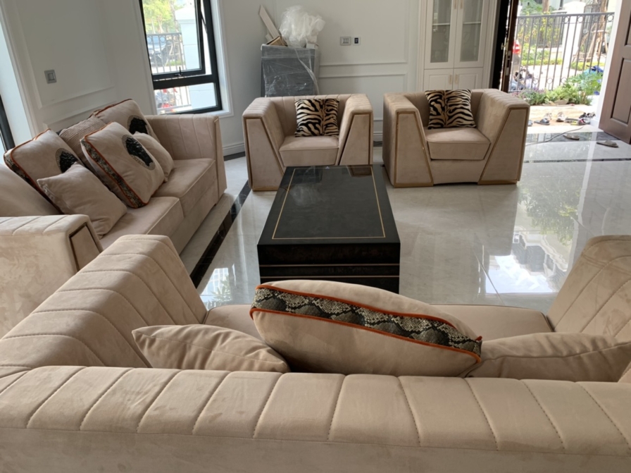 Góc nhìn cận cảnh bộ sofa phòng khách bọc nỉ màu kem, với các chi tiết may chần tinh tế trên bề mặt. Gối tựa trang trí họa…