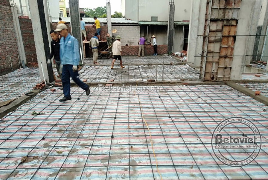 Không gian sàn bê tông cốt thép đang được chuẩn bị, với hệ thống cốt thép đan xen và cốp pha. Bố cục ảnh từ trên cao, cho…