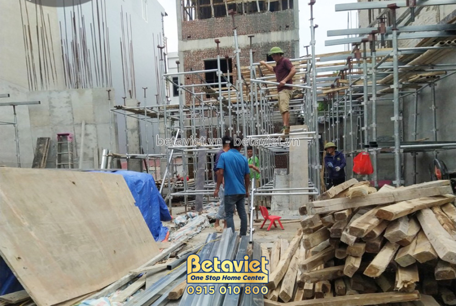 Công nhân đang làm việc trên giàn giáo, chuẩn bị cho việc đổ sàn tầng 1. Vật liệu xây dựng như gỗ, thép được tập kết tại c…